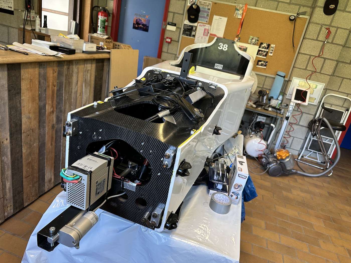 A formula car carbon monocoque being converted into a motion simulator, with actuator and power electronics fitted.